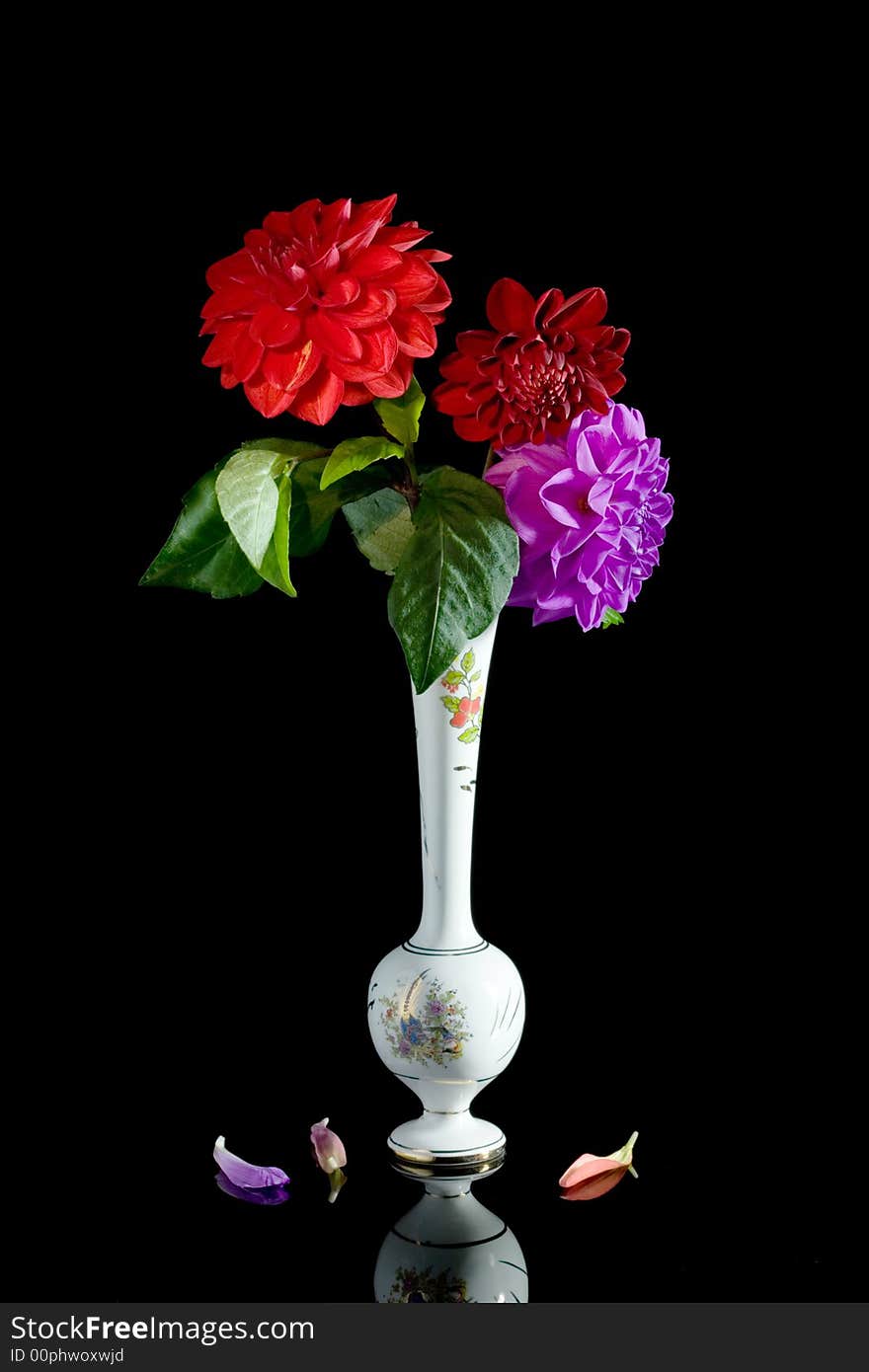 Vase of three red dahlias.