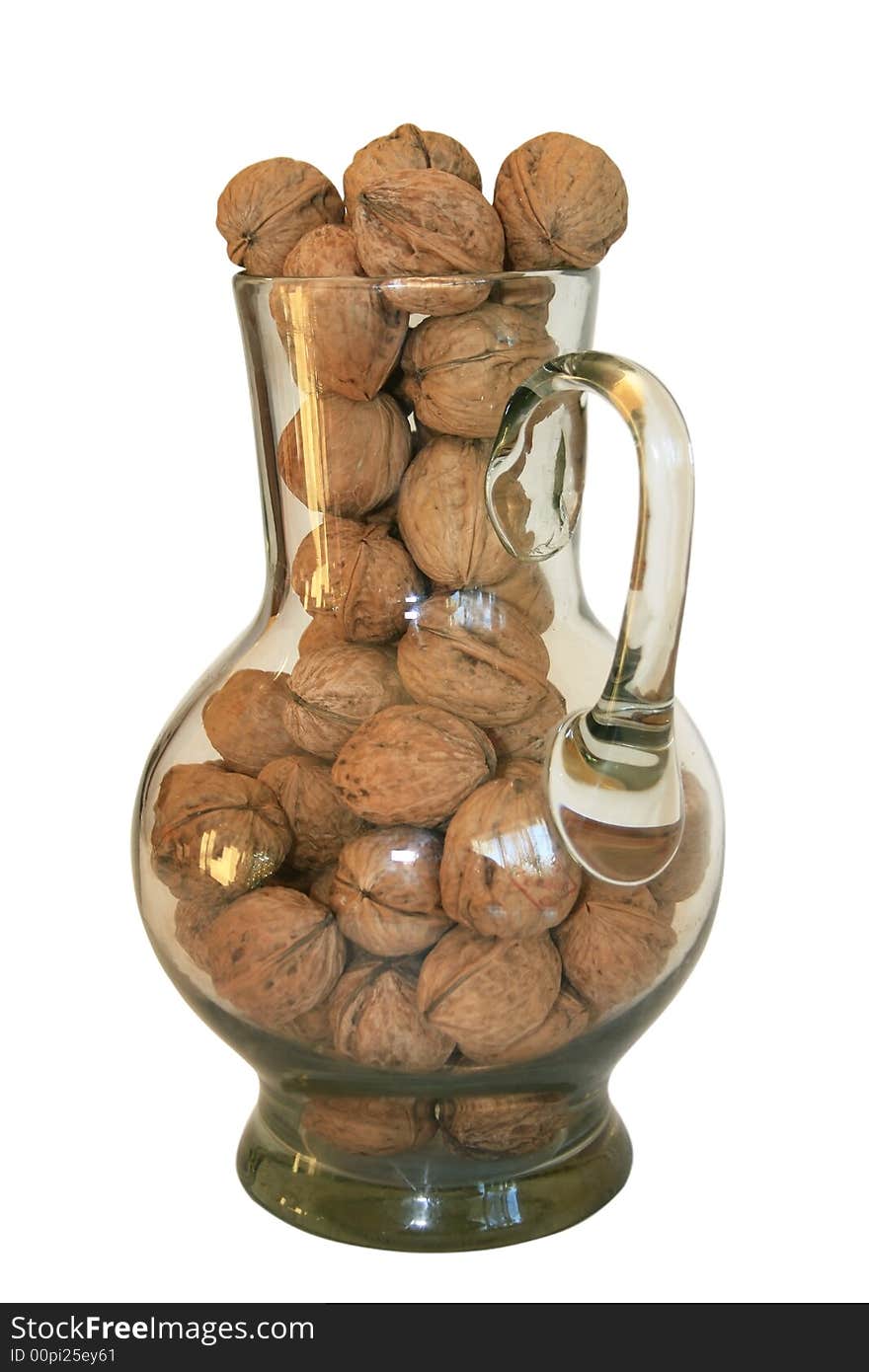 Handful of walnuts in a glass decanter on a white background