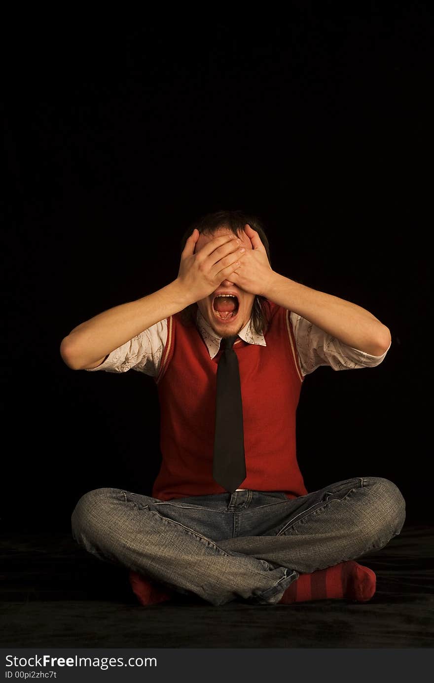 Man on the black background with closed eyes. Background material is a black velvet with reflexes from red sweather. Man on the black background with closed eyes. Background material is a black velvet with reflexes from red sweather.