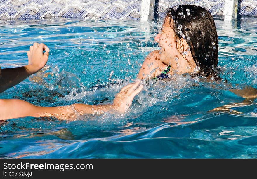 Girls playing and having fun in the swimming pool. Splashes of water. Girls playing and having fun in the swimming pool. Splashes of water.