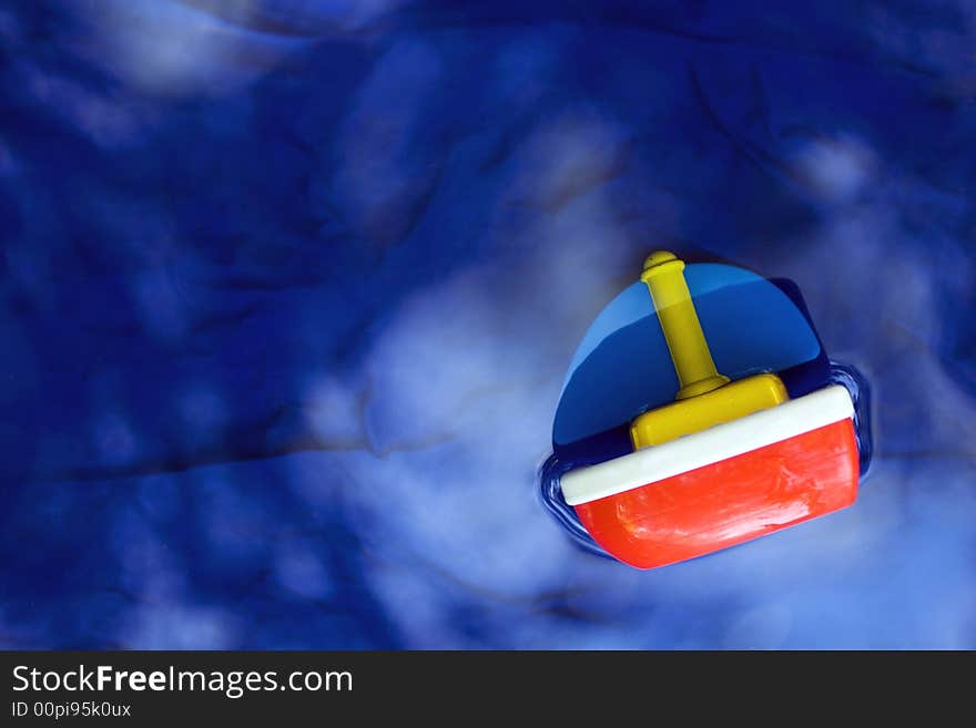 A color photograph of a toy ship in water. A color photograph of a toy ship in water.