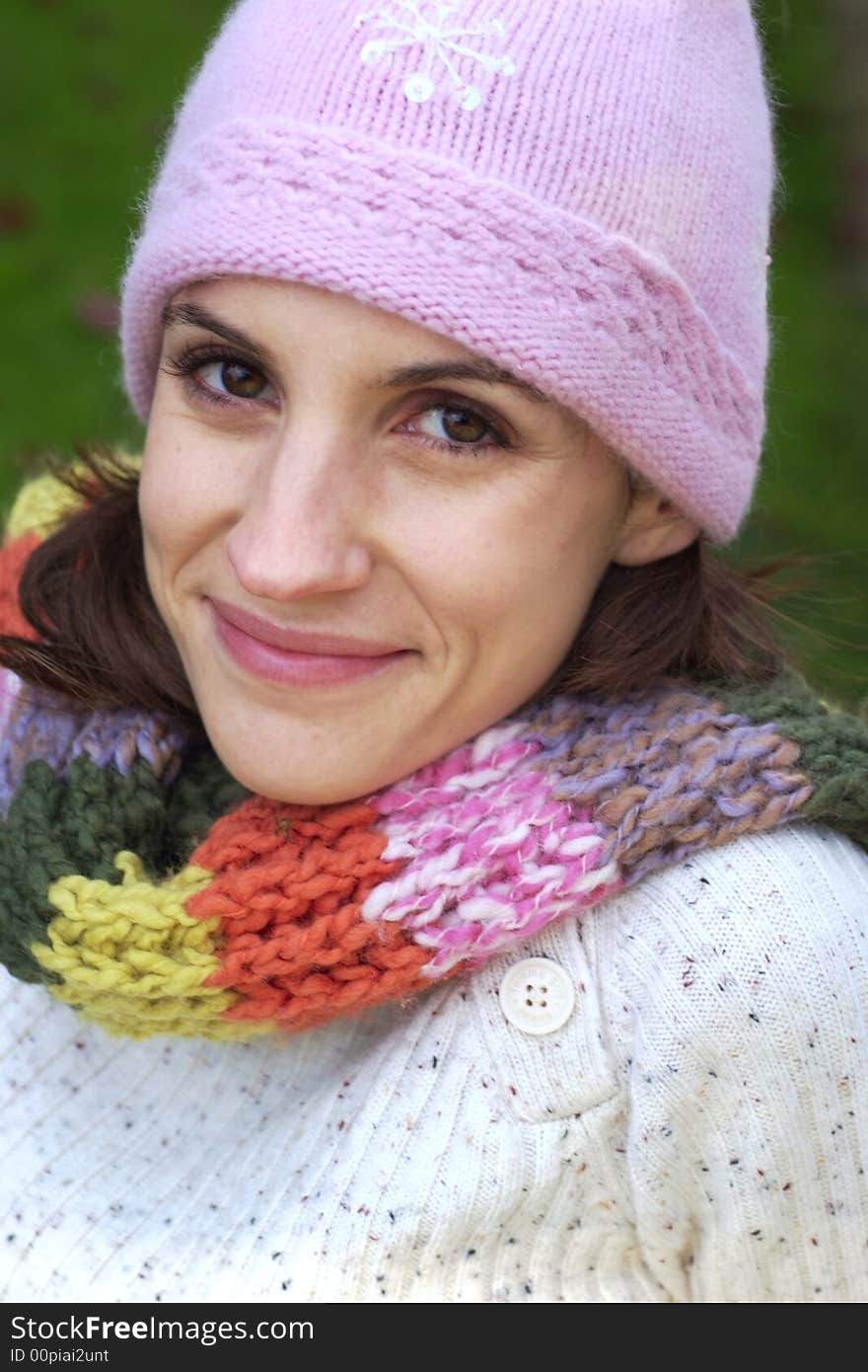 A beautiful woman wearing a multi-color scarf, sitting on a bench, and wearing a bonnet. A beautiful woman wearing a multi-color scarf, sitting on a bench, and wearing a bonnet.