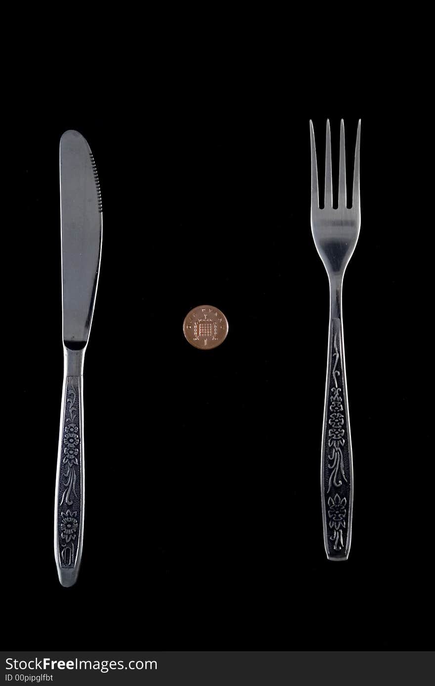 One penny lying between fork and knife. One penny lying between fork and knife