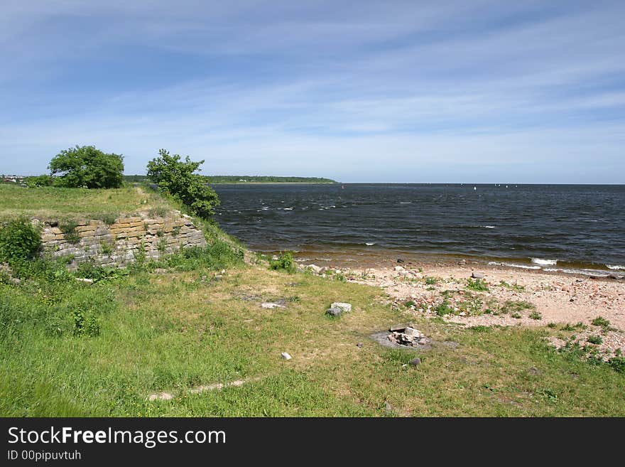 Stoned river coastline with ruins remains and grass