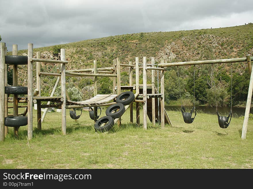 A child's play ground with a climber, a tree and a bathroom in the background. A child's play ground with a climber, a tree and a bathroom in the background