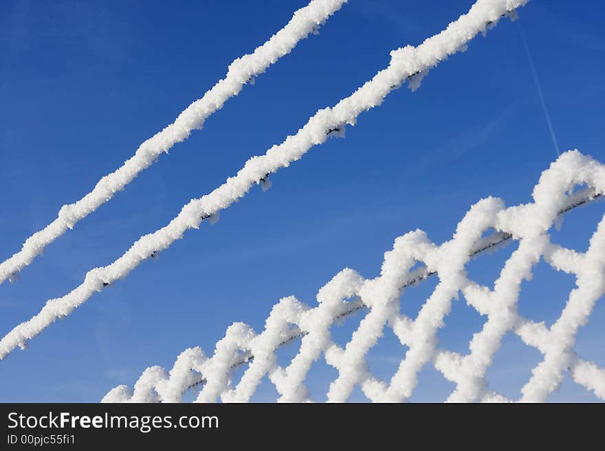 Snow fence in winter landscape with bright blue sky in background