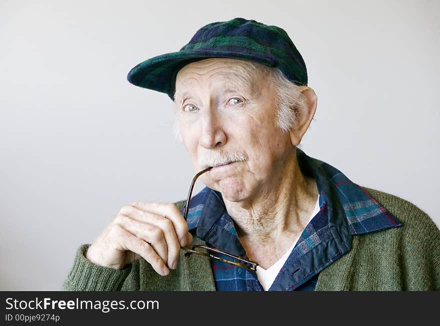 Portrait of a thoughtful senior citizen with glasses wearing a hat. Portrait of a thoughtful senior citizen with glasses wearing a hat.