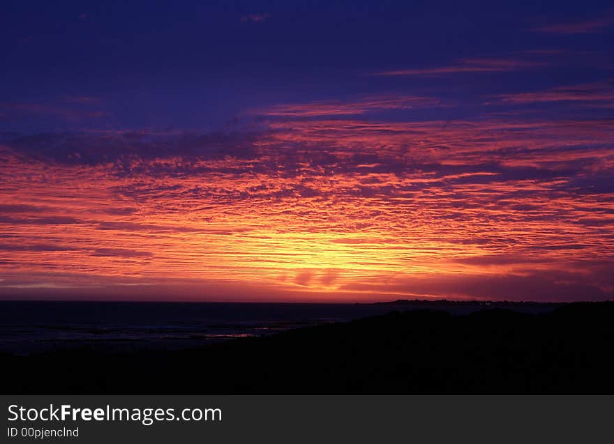 Beautiful sunset by the sea with colourful fluffy clouds