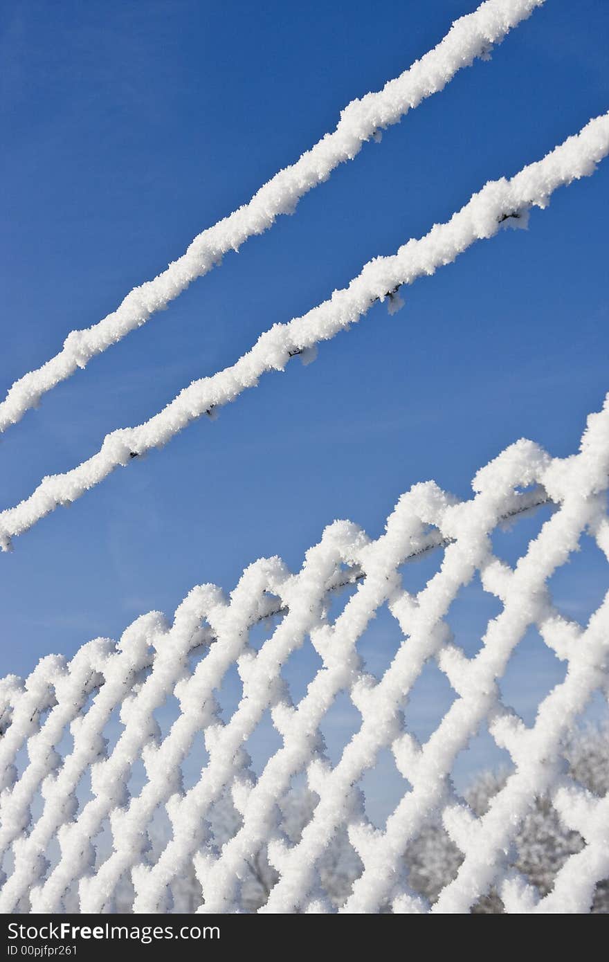 Snow fence in winter landscape with bright blue sky in background