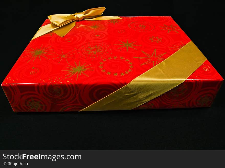 Chocolate candy in red gift box with golden ribbon - isolated on black