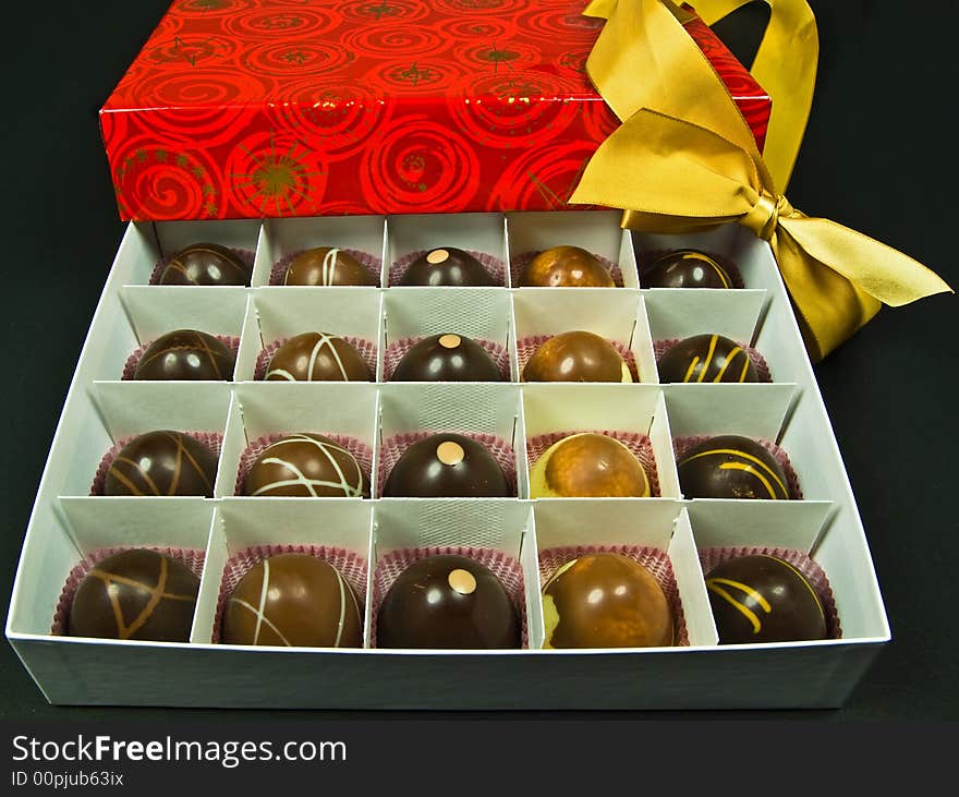 Chocolate candy in red gift box with golden ribbon - isolated on black