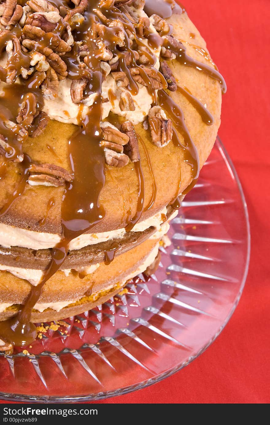 Sweet pumpkin cake dessert with cream filling and pecans on top drizzled with caramel topping on clear plate. Sweet pumpkin cake dessert with cream filling and pecans on top drizzled with caramel topping on clear plate