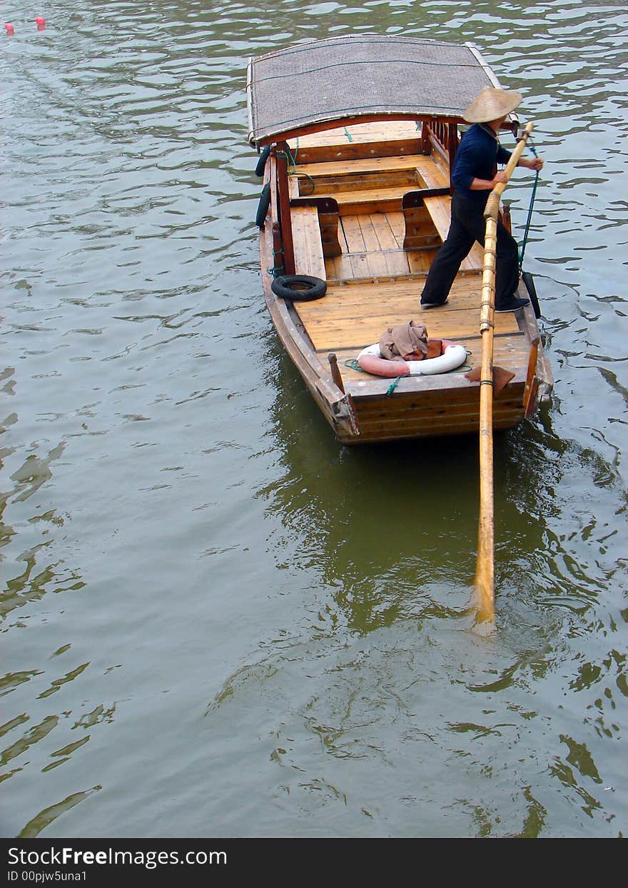 Boatman in Suzhou canal sculling boat. Location in China.