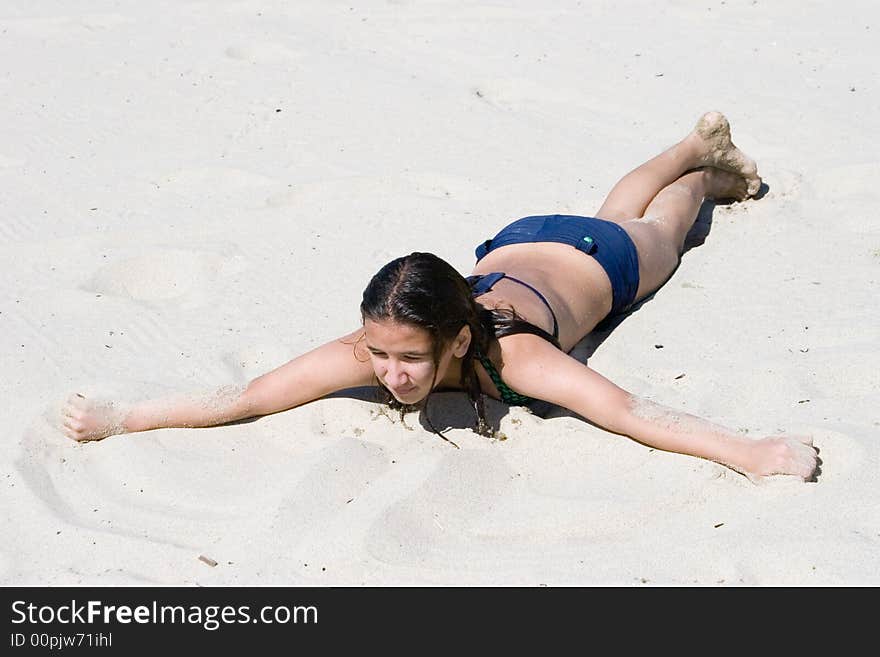 Girl lays on the sunny sand beach, warming up on hot sand after long swimming