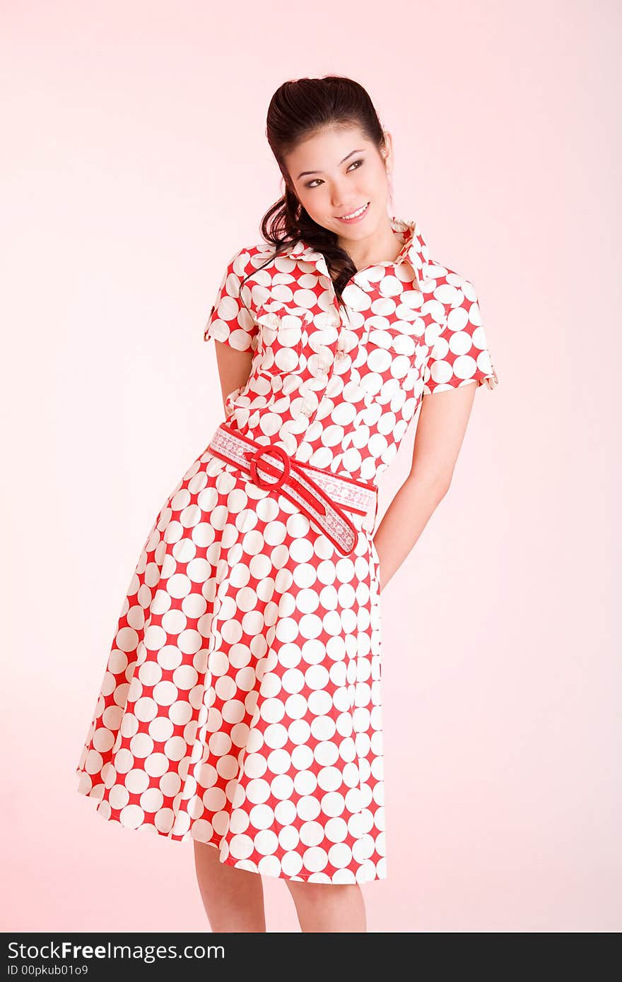 Smiling woman in red with white polka dots dress looks side way. Smiling woman in red with white polka dots dress looks side way