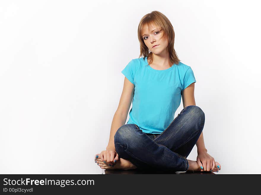 The girl sits on a table having crossed legs