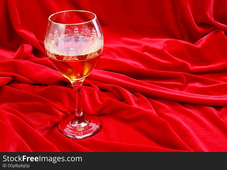 Golden wine in glass on red velvet. Golden wine in glass on red velvet