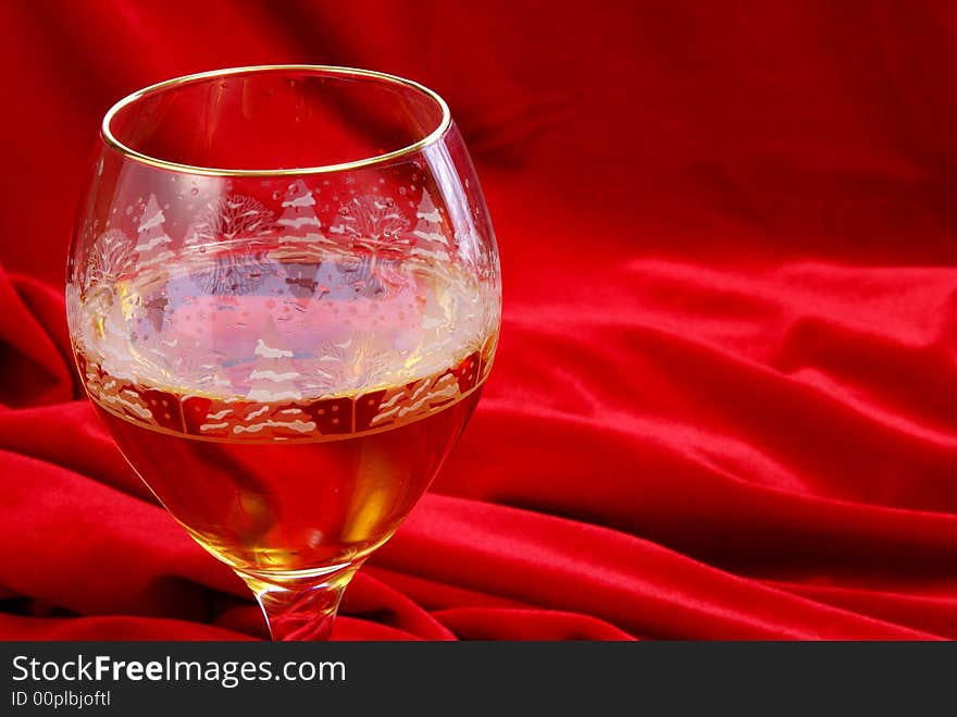 Golden wine in glass close up on red velvet. Golden wine in glass close up on red velvet