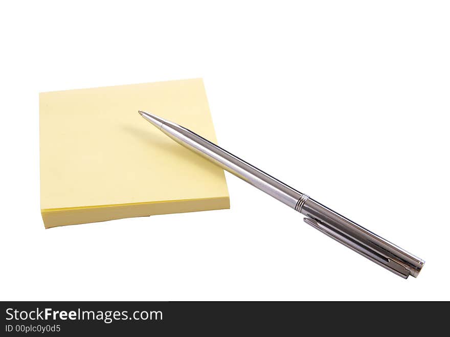 Isolated yellow notepaper pad with silver pen on white background. Isolated yellow notepaper pad with silver pen on white background