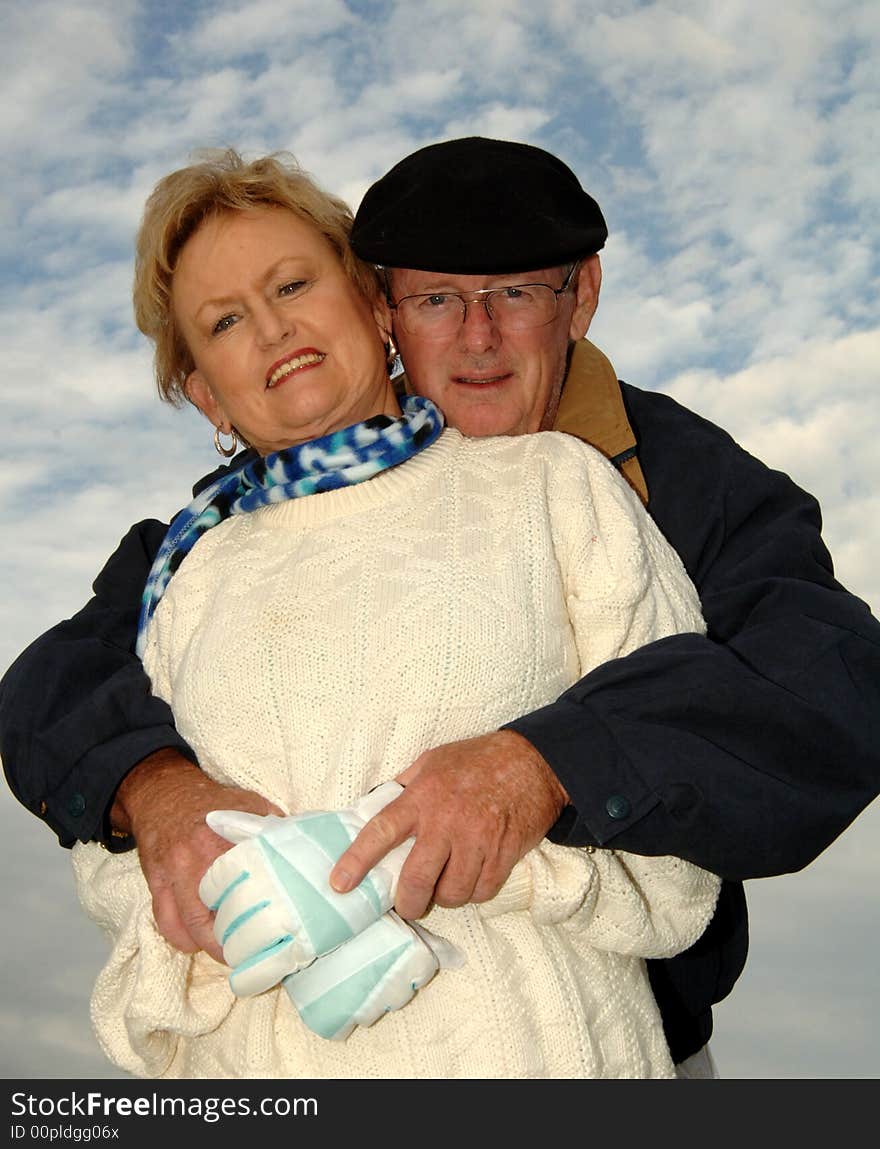 Senior man with his arms around a senior woman keeping her warm. Senior man with his arms around a senior woman keeping her warm.