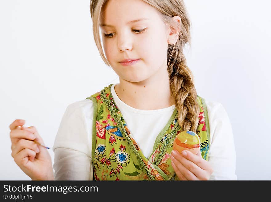 Studio portrait of a young blond girl who is painting eggs for easter. Studio portrait of a young blond girl who is painting eggs for easter