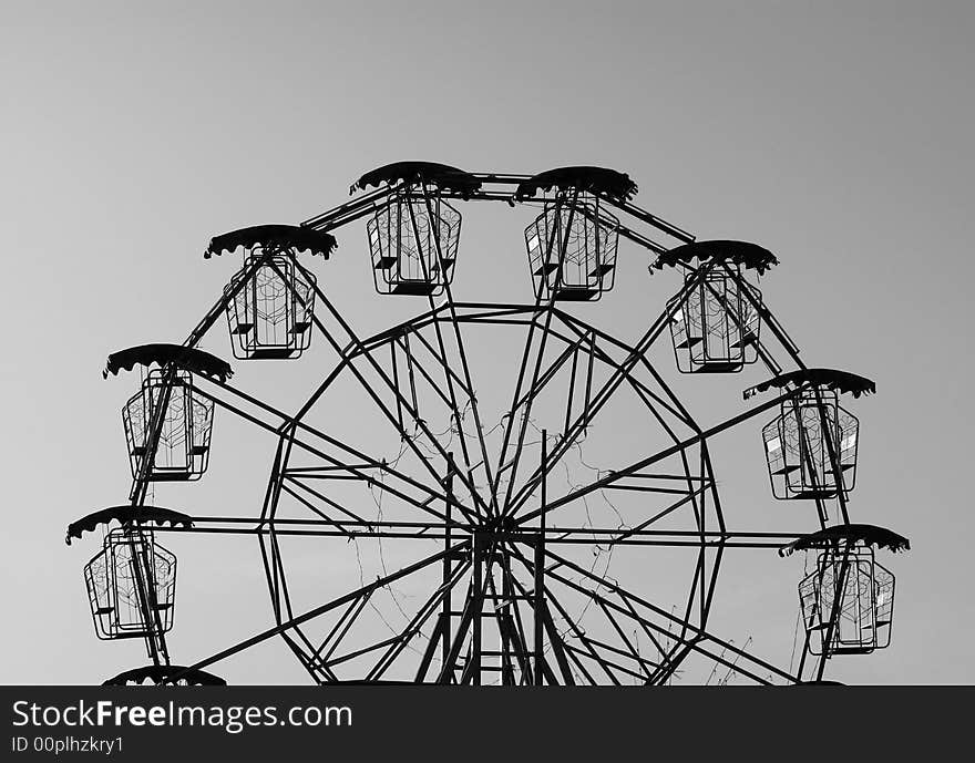 Silhouette of a small ferris wheel. Black and white photo.