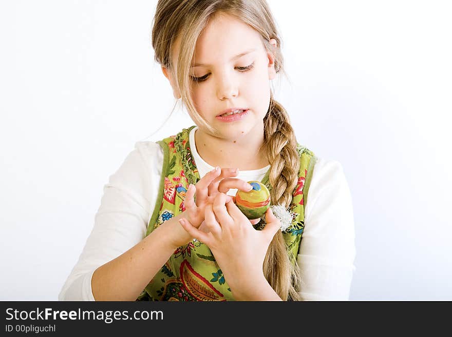 Studio portrait of a young blond girl who is examining her painted easter egg. Studio portrait of a young blond girl who is examining her painted easter egg