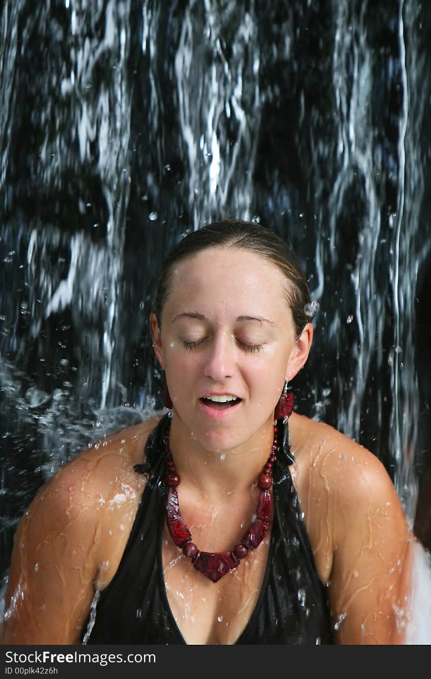 A young woman relaxes under a waterfall at a five star spa in Costa Rica. A young woman relaxes under a waterfall at a five star spa in Costa Rica