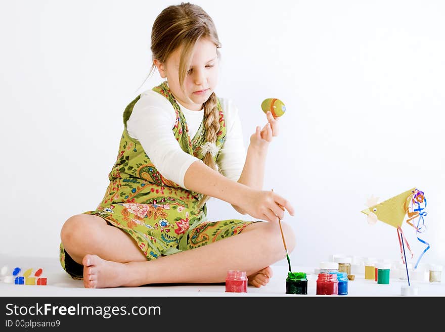 Studio portrait of a young blond girl who is playing with paint and eggs for easter. Studio portrait of a young blond girl who is playing with paint and eggs for easter