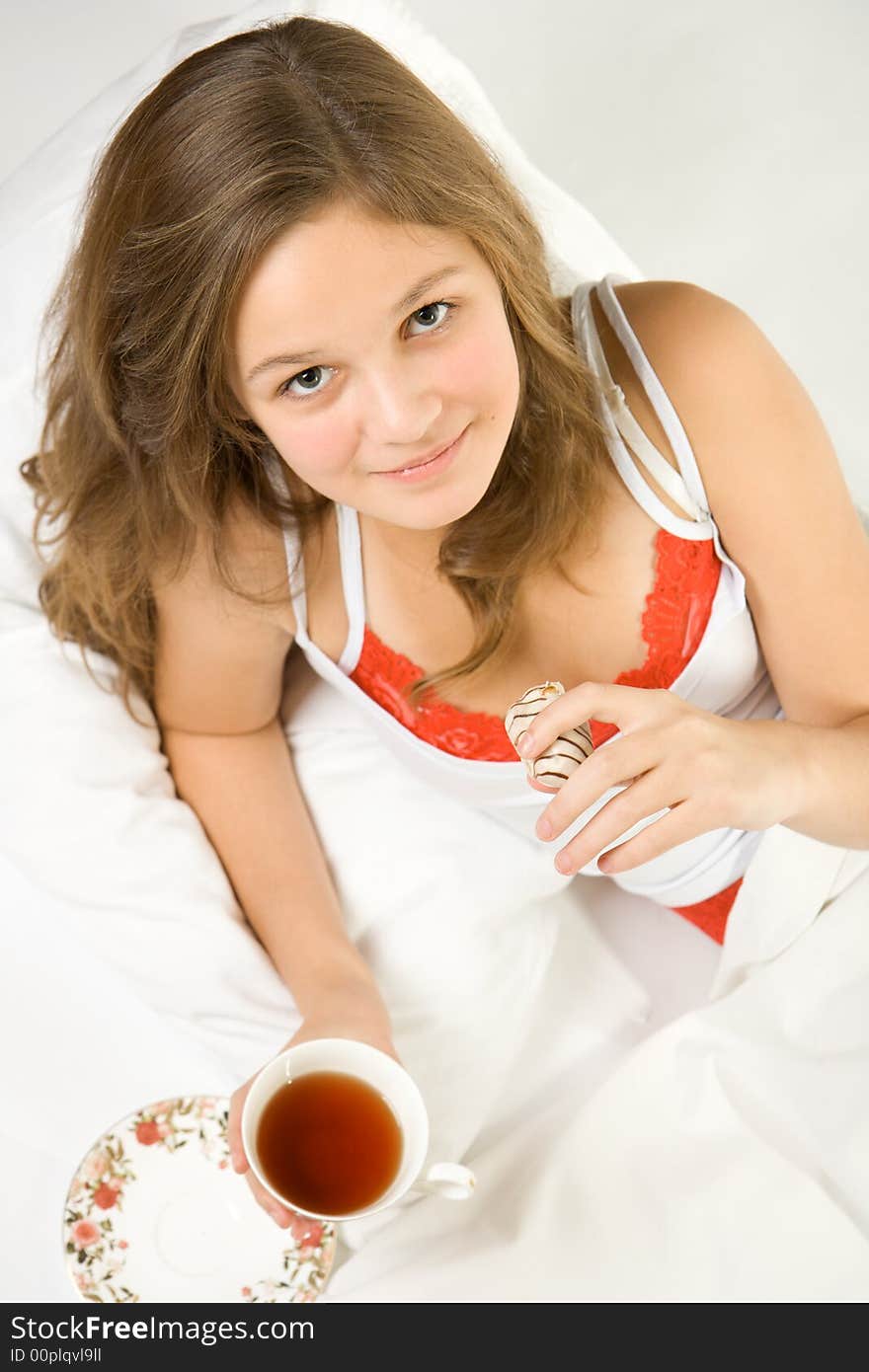 Young girl drinking tea in the bed