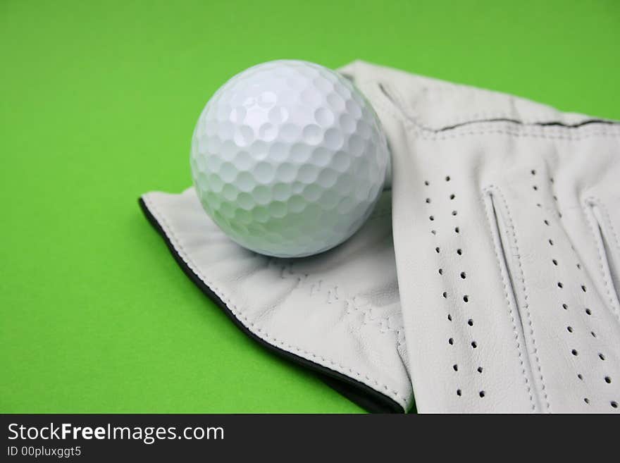 Golf glove and ball on a green background