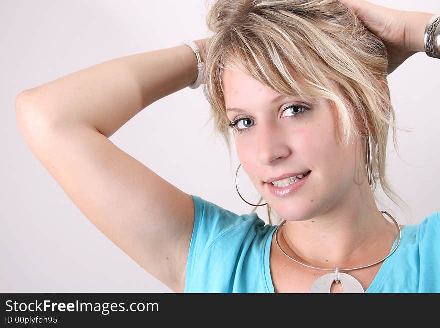 Blonde Female model taking up her hair to tie with a hair band. Blonde Female model taking up her hair to tie with a hair band