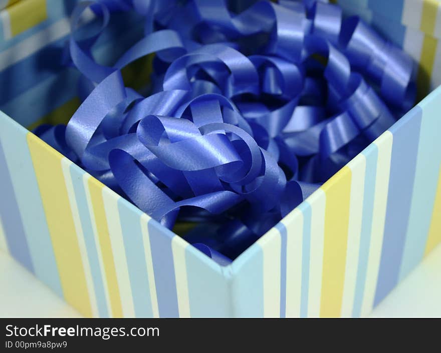 A striped box full of curly blue ribbon. A striped box full of curly blue ribbon.