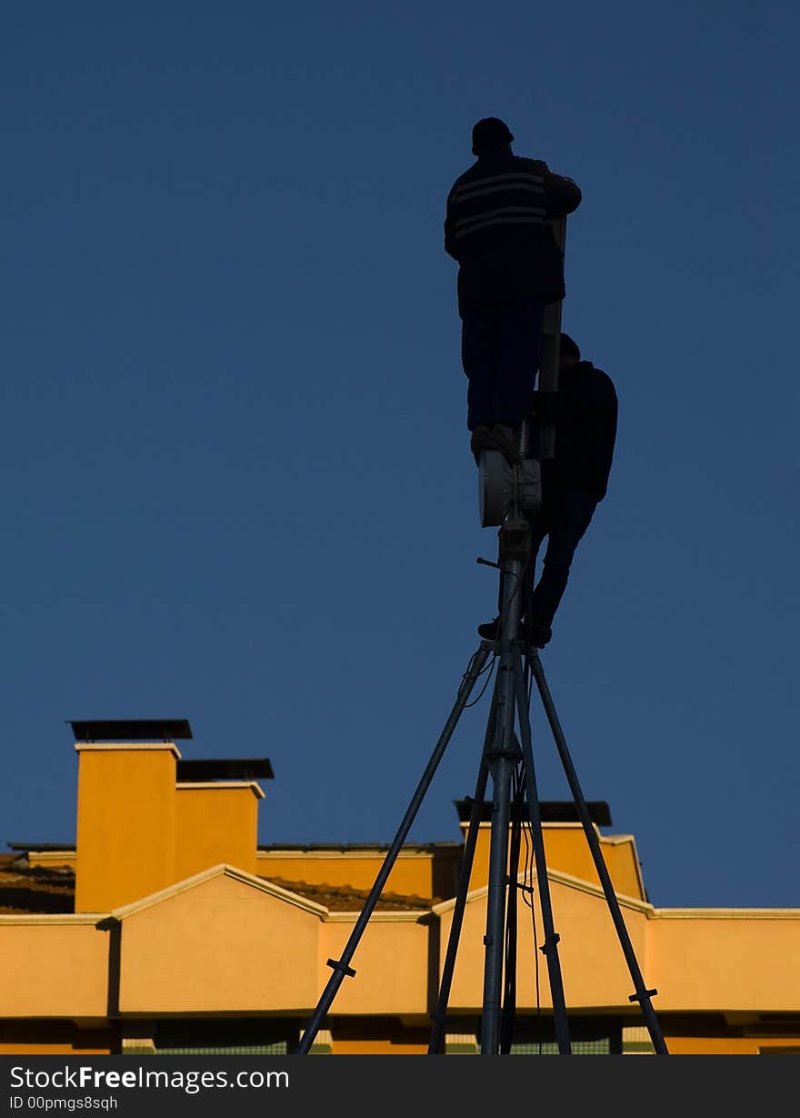 Silhouette of two technician working on the roof