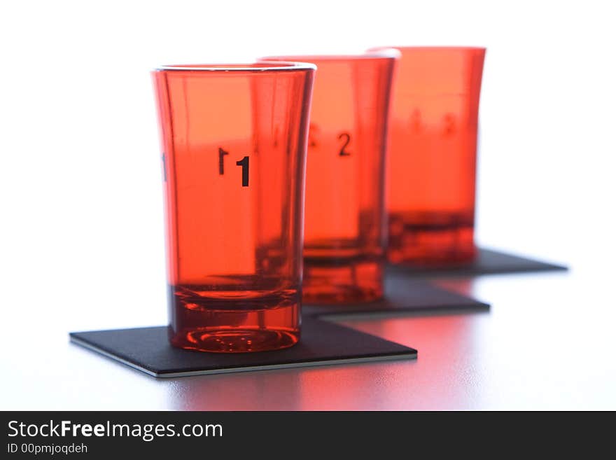 Three red glass numbered glasses on black supports