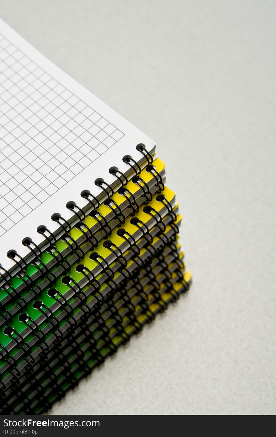 Pile of notebooks with sheets in a cell fastened by a spring.