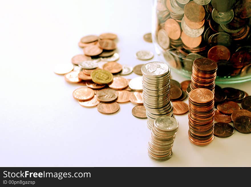 Stacks of american coins, jar of coins, white background. Stacks of american coins, jar of coins, white background