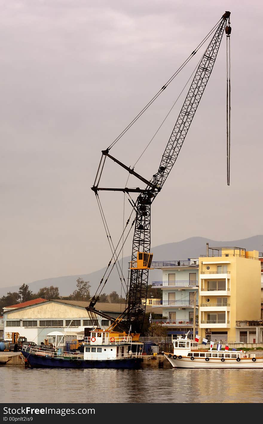 Image shows an industrial crane over a Mediterranean port