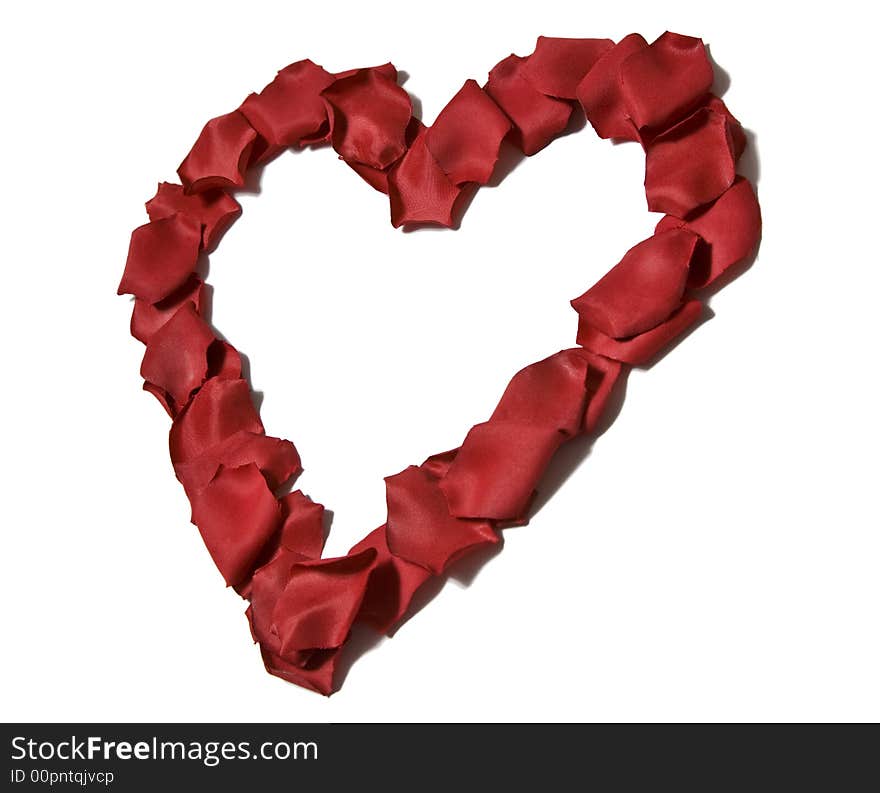 Red silk rose petals in a heart shape isolated on a white background. Red silk rose petals in a heart shape isolated on a white background.