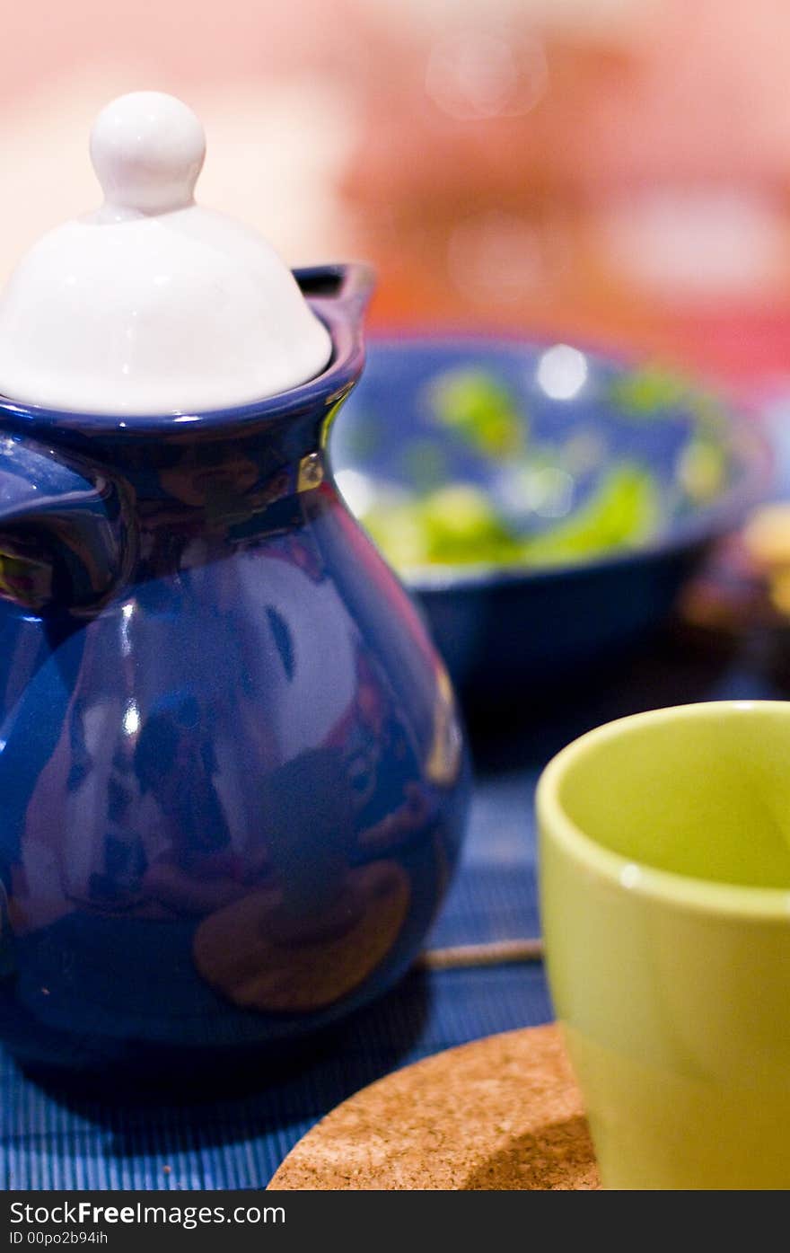 A blue teapot and a yellow cup. A blue teapot and a yellow cup.