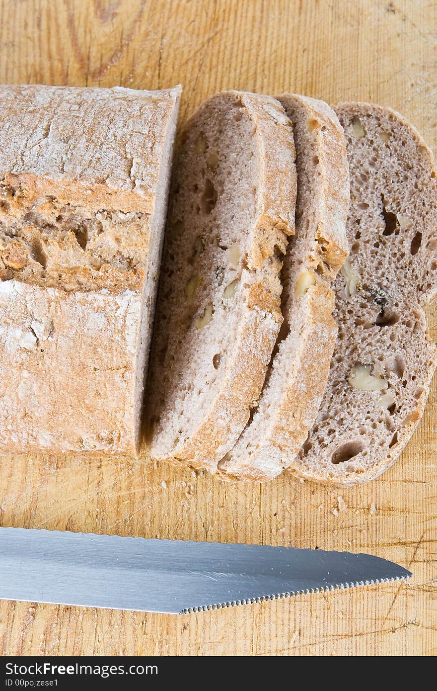 A fresh bread loaf with a knife on a wooden board