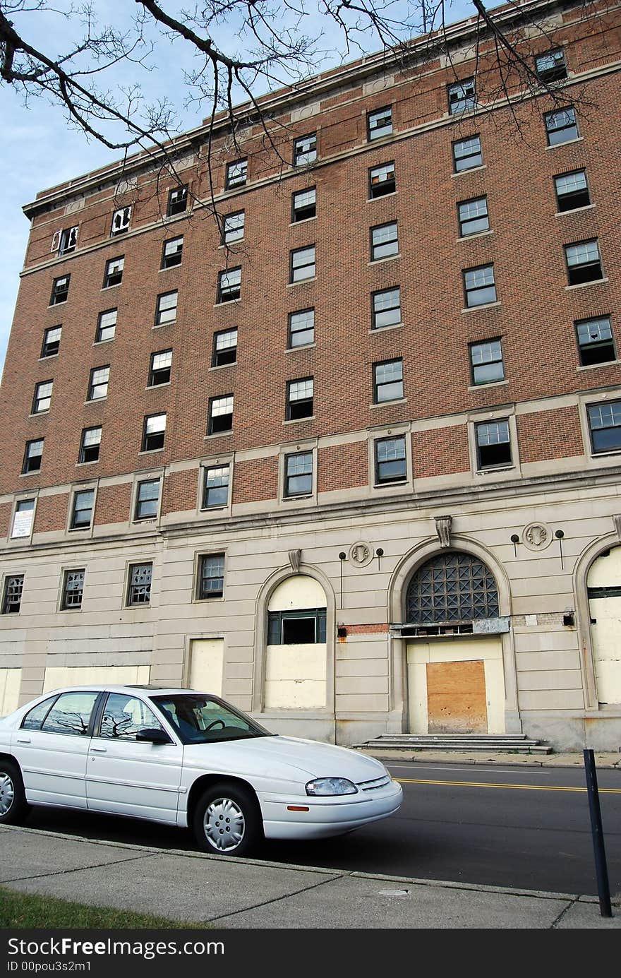 A car parked on the street in front of an old abandoned building. A car parked on the street in front of an old abandoned building.