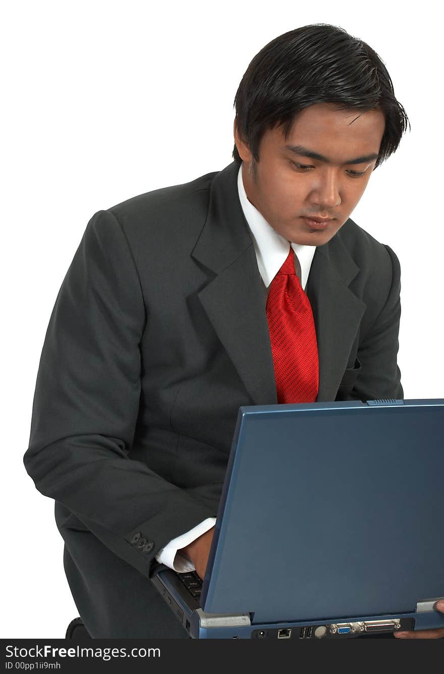 A man sitting while working on his laptop computer