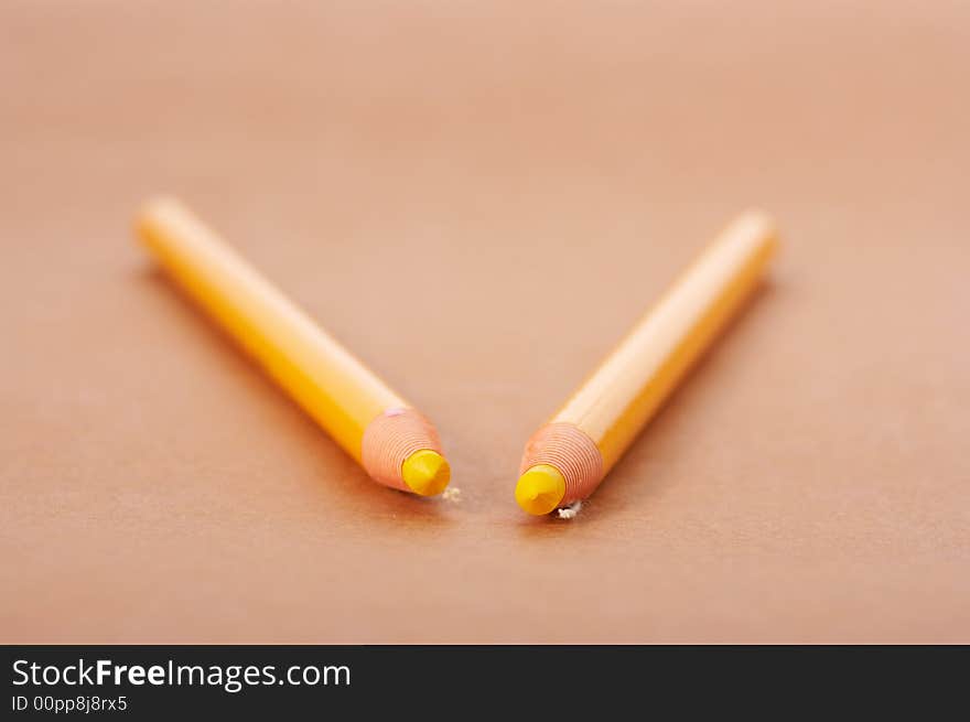 Two yellow pencil on a brown paper