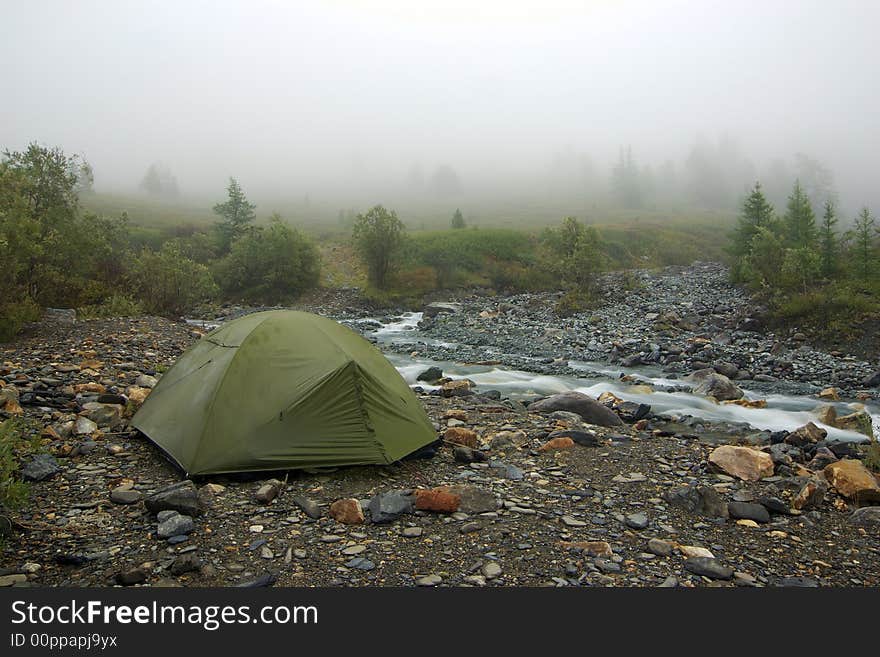 Morning camp and fog near mountain river