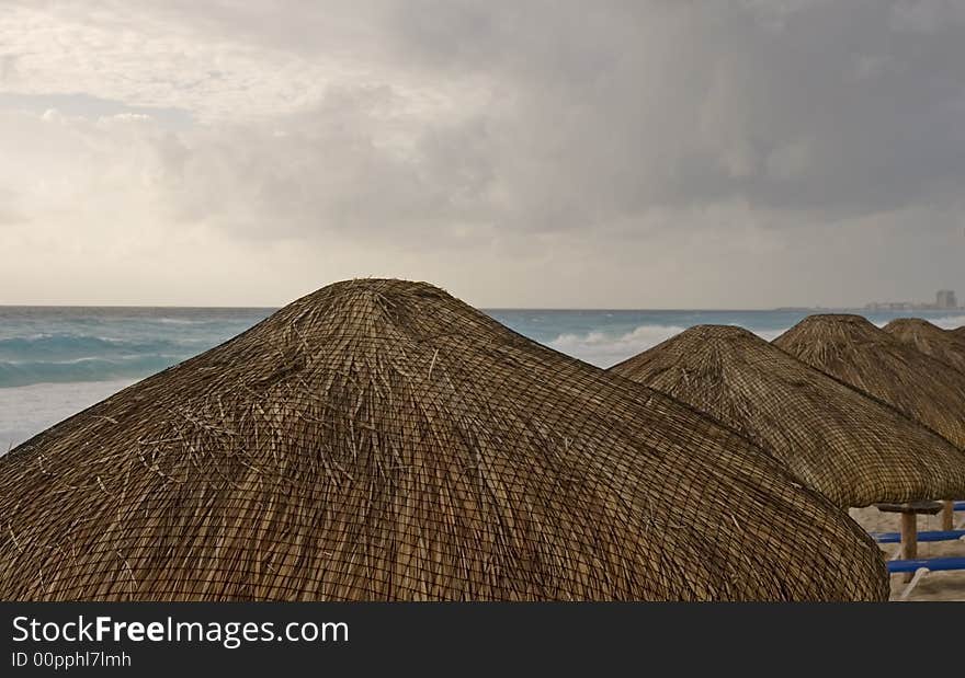 Thatched roofs of beach huts in front of a stormy sky and rough sea. Thatched roofs of beach huts in front of a stormy sky and rough sea