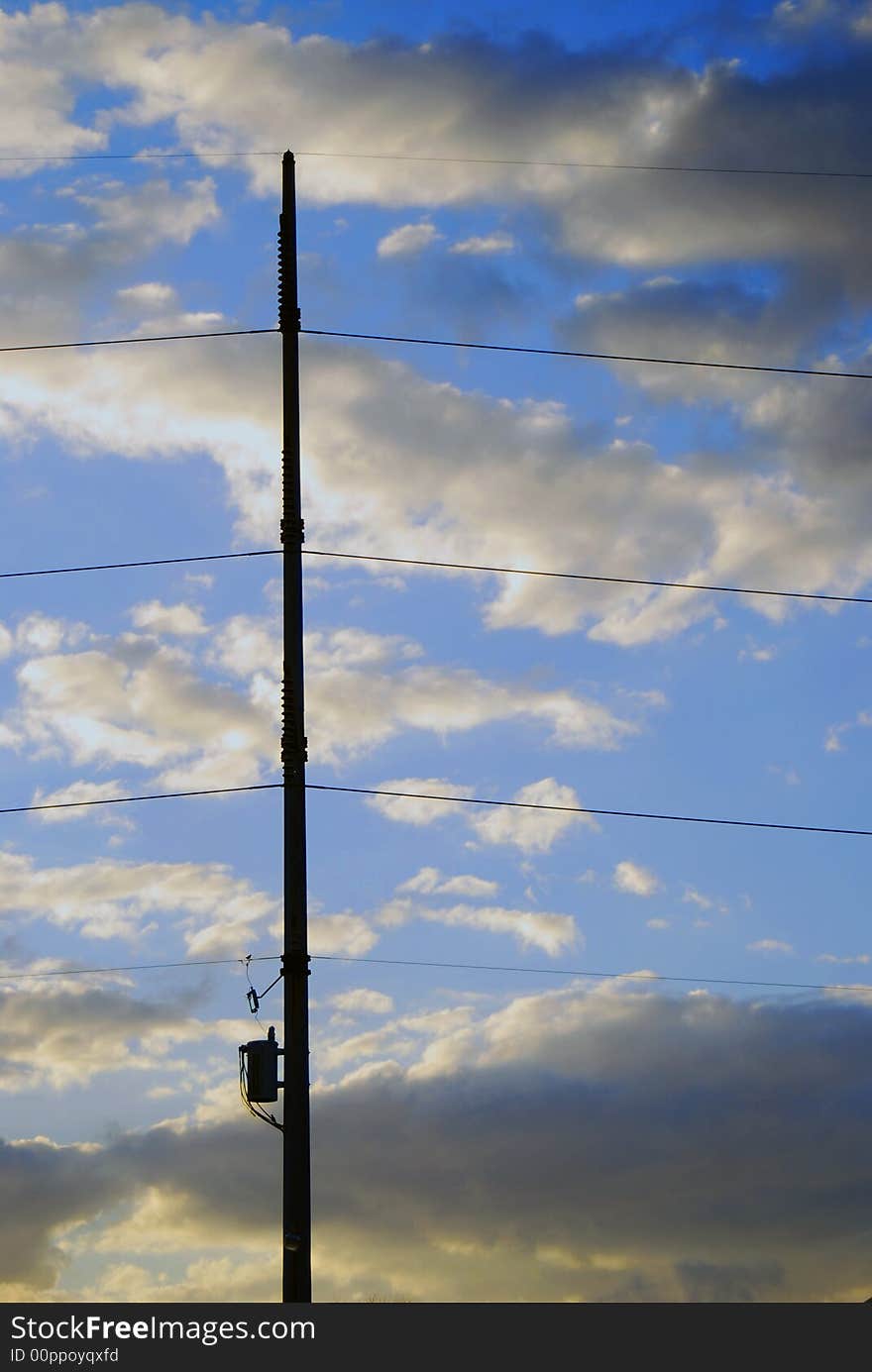 Transformer and power lines are held in place by pole and magnificent cloudscape at sunset. Transformer and power lines are held in place by pole and magnificent cloudscape at sunset.