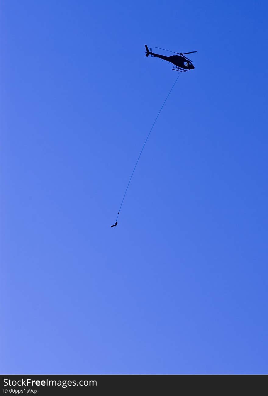 A helicopter air lifts an injured person on a long line beneath the aircraft in a dramatic rescue high in the mountains. A helicopter air lifts an injured person on a long line beneath the aircraft in a dramatic rescue high in the mountains.