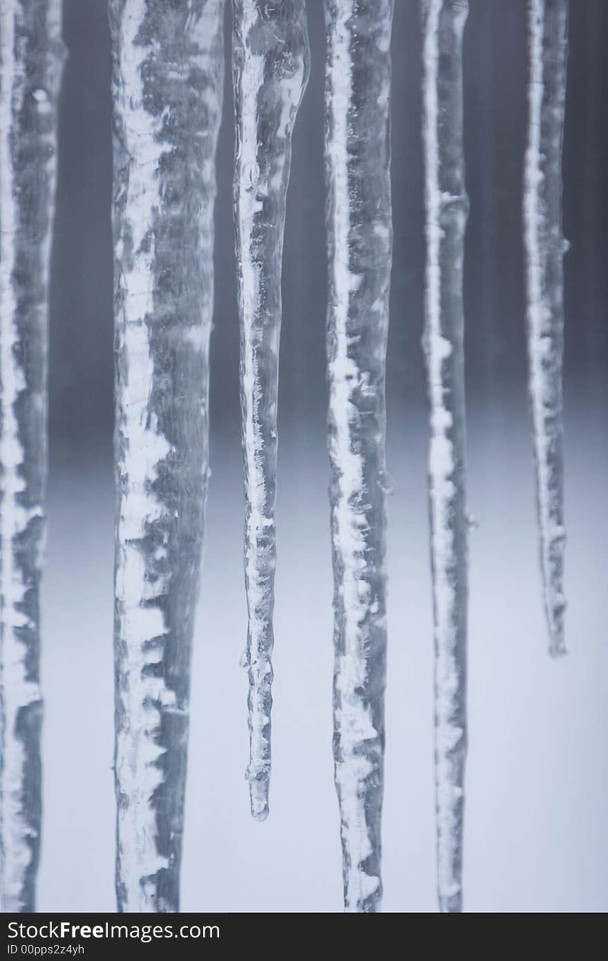 Icicles hang from a roof top catching and reflecting light through the window on a winter day. Icicles hang from a roof top catching and reflecting light through the window on a winter day.