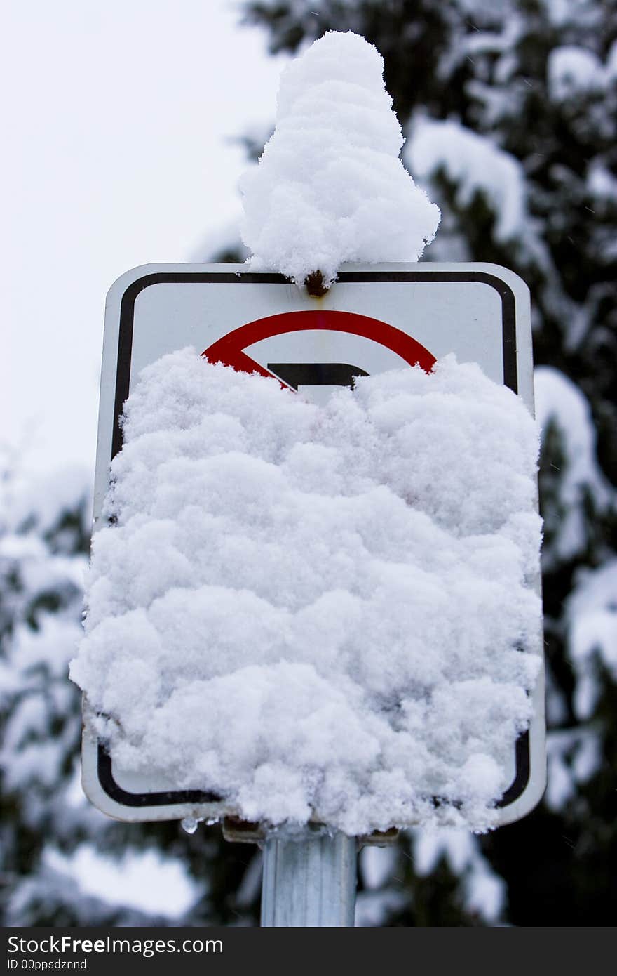 A sign warning drivers not to park cars on the road is obscured by a winter storm. A sign warning drivers not to park cars on the road is obscured by a winter storm